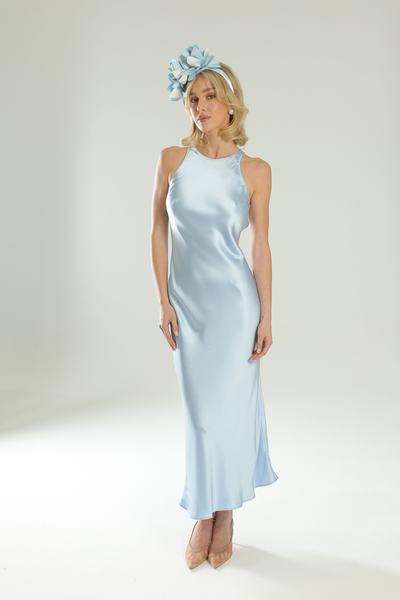 Woman wearing a light blue satin dress with a matching headband on a white background